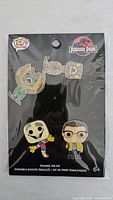 Front of sealed Funko Pop Jurassic Park enamel pin set showing four pins on black backing card.