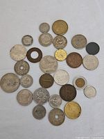 Top-down photo showing entire assortment of coins spread on white background, exhibiting varied sizes, colors, and hole designs.