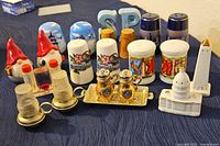 Photo showing a variety of salt and pepper shakers including gnome figurines, lighthouses, oil and vinegar cruets, and ceramic shakers with painted scenes.