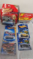 Photo showing 7 die cast cars from Johnny Lightning and Hot Wheels, some in original packaging, some loose.