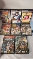 Photo of eight PlayStation 2 games arranged in two rows, all in original cases showing cover artwork and titles.