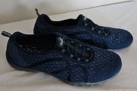 Side view of pair of black Skechers Relaxed Fit sneakers showing knit texture and sole profile.