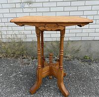 Side view of an antique walnut wood Eastlake style side plant table with carved apron and turned legs.