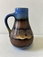 Single ceramic ewer vase in West German Fat Lava style, showing handle and colorful layered glaze in blue, brown and beige tones