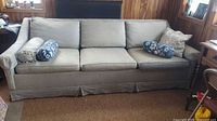 Front view of light gray 3-seat sofa with three cushions and skirted base