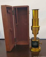 Microscope beside open hinged wood box