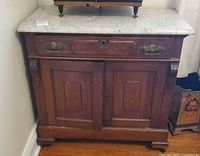 Front view showing marble top, drawer, doors, brass hardware