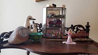 Lot overview on table showing curio cabinet and surrounding collectibles