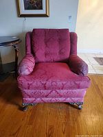 Front view of burgundy damask club chair showing tufted back, padded arms, carved wooden feet