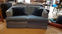 Front view of blue loveseat with black pillows