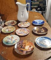 Group shot of white pitcher and nine assorted decorative plates
