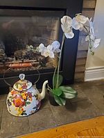 Teapot and orchid together in front of fireplace