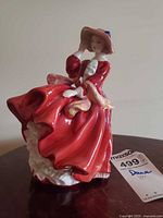 Three-quarter front view of figurine showing red dress, hat and front details