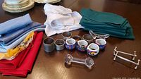 Full lot showing napkin rings, knife rests and stacks of multicolour cloth napkins