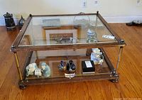 Oblique view showing top glass surface, lower shelf, frame, brass posts and feet