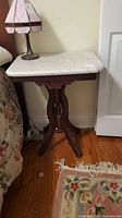 Full view of marble-top side table beside bed