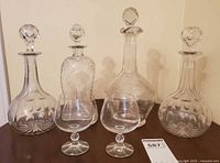 four decanters with stoppers and two snifters on table