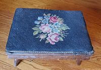 Top view showing embroidered floral needlepoint cushion on wooden footstool
