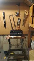 Overall view showing Workmate bench, toolbox, mounted saws, clamp and level