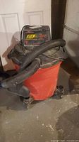 Front view of Craftsman red drum wet/dry vacuum with hose and casters visible