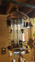 Double-tube copper-tone glass bird feeder hanging from ceiling