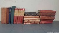 Full group of approx. 20 cloth hardcover books in mixed colours, stacked and upright