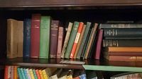 Shelf of mixed hardcover books, first section visible spines