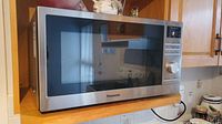Front view of Panasonic stainless steel microwave installed on shelf