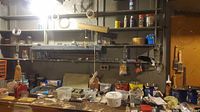 Workshop bench with orange organizer, bench vise, red press, clear bins and assorted hardware visible