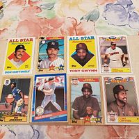 Photo shows 8 vintage MLB baseball cards arranged in two rows on a floral background, featuring Don Mattingly, Bo Jackson, Tony Gwynn, and Mark McGwire in colorful All-Star and rookie card designs.