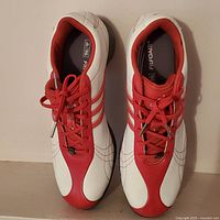 Top view of both new Adidas golf shoes showing white and red color, Adidas stripes on sides, and FitFoam insoles.