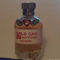 Front view of perfume bottle showing brand and design details including heart with wings and '25' on label.