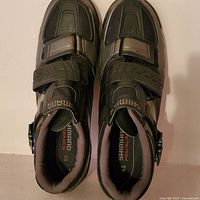 Top down view of both black Shimano clip on cycling shoes showing size 45 label and fastening straps.