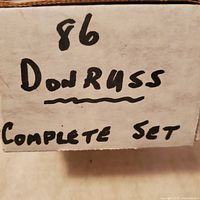Close up of handwritten label on the box reading '86 Donruss Complete Set',' showing lot content indication.