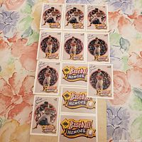 Twelve vintage Reggie Jackson Baseball Heroes sports cards arranged on floral fabric background showing various cards with Reggie Jackson in baseball poses and Baseball Heroes logo cards.