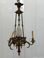 Full view of chandelier showing three arms, central torch light, rope supports