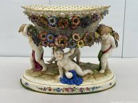Side view of porcelain centrepiece showing cherubs, applied flowers and base details