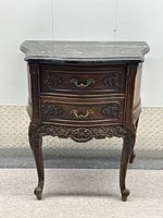 Full front view of carved two-drawer table with marble top