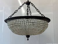 Full view of brass and crystal basket chandelier hanging from chains