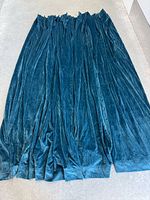 Four teal blue velvet curtain panels laid out to show overall size and color