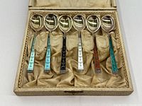 Six sterling silver demitasse spoons with multicolored enamel handles displayed in fitted case