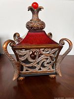 Front view showing metal scroll patterns and side handles with red glass panels.