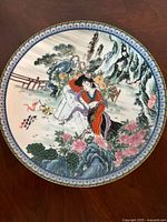 Top-down image showing full porcelain plate with painted Asian woman and garden scenery design.