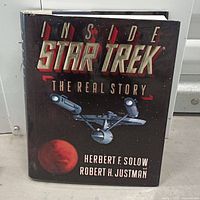 Front cover of the hardcover book showing the title 'Inside Star Trek The Real Story' with an image of the USS Enterprise and a planet, authors Herbert F. Solow and Robert H. Justman listed.