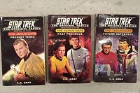Front covers of three Star Trek paperback novels showing title, author L.A. Graf, and cover artwork with main characters in Starfleet uniforms.