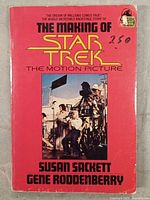 Front cover of the book with pink background and film crew photo. Visible handwritten price '2.50' on top right corner.