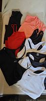 Eight activewear garments arranged on surface showing sports bras and tops