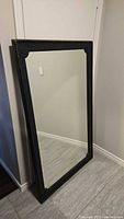 Full view of rectangular mirror leaning against wall