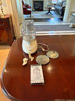 Food processor and accessories arranged on wooden table, showing the unit with multiple blades, discs, and instructional video cassette.