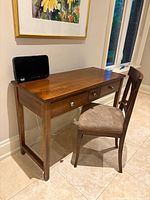 Desk next to chair positioned against wall showing side and front with drawers visible
